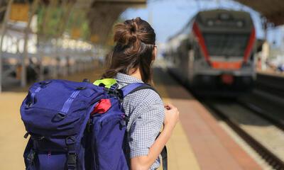 jongere met rugzak wacht op trein in treinstation