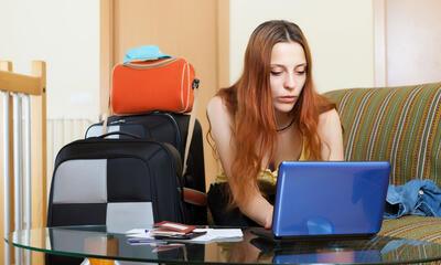 vrouw met laptop en koffers