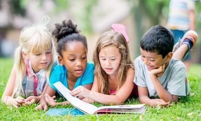 Kinderen lezen boek in het gras
