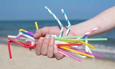 Plastic rietjes in hand op strand