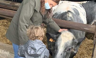 Zuhal Demir met dochter bij een koe op bezoek bij een landbouwer
