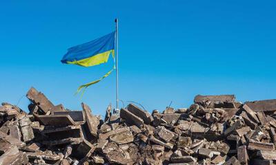 brokstukken van vernield gebouw en gescheurde Oekraïense vlag
