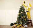 Kind in geel kerstpak zet vlaggetje op kerstboom