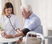 verpleegster neemt bloeddruk bij oudere man